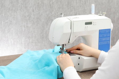Seamstress working with sewing machine at table indoors, closeupの写真素材