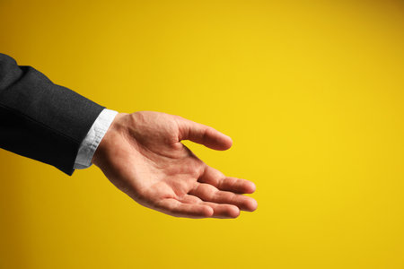 Man holding something in hand on yellow background, closeup. Space for textの写真素材