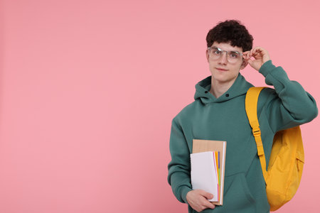 Portrait of student with backpack and notebooks on pink background. Space for textの写真素材