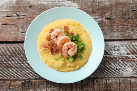 Plate with fresh tasty shrimps, bacon, grits and green onion on wooden table, top viewの写真素材