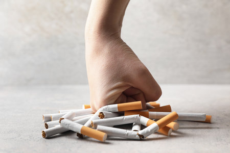 Stop smoking. Woman crushing cigarettes at gray table, closeupの写真素材