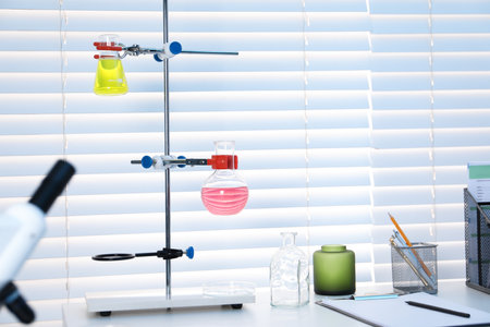 Laboratory analysis. Stand with flasks of liquids on white table indoorsの写真素材