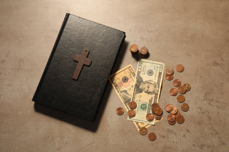 Donate and give concept. Coins, Bible, cross and dollar banknotes on gray table, flat lay