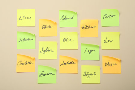 Paper stickers with different names on beige background, flat lay. Choosing baby's nameの写真素材
