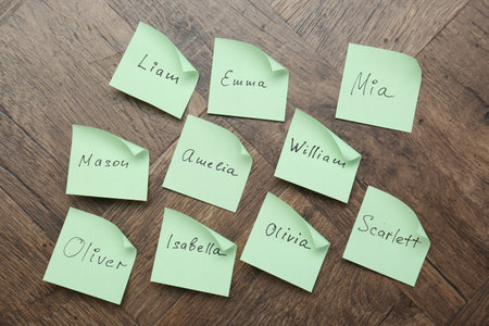 Paper stickers with different names on wooden background, flat lay. Choosing baby's nameの写真素材