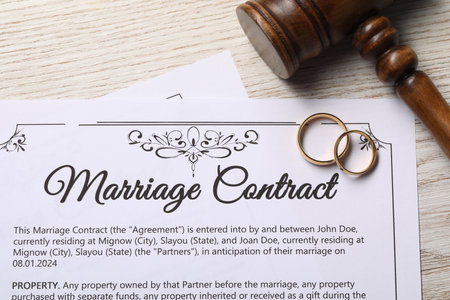 Marriage contract, golden wedding rings and gavel on wooden table, top viewの写真素材