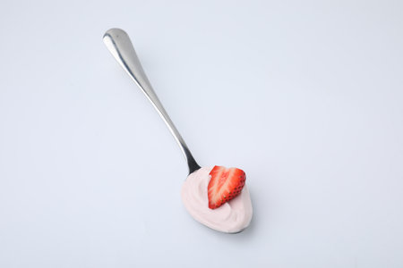 Delicious natural yogurt with fresh strawberry in spoon on light backgroundの写真素材