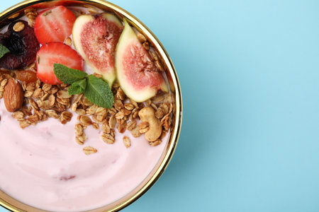 Bowl with yogurt, fruits and granola on light blue background, top view. Space for textの写真素材