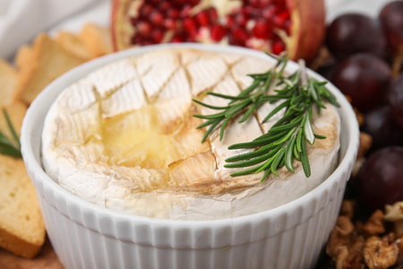 Tasty baked camembert and rosemary in bowl on blurred background, closeupの写真素材