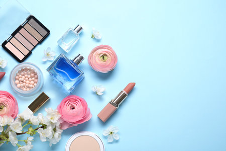 Flat lay composition with different makeup products and beautiful spring flowers on light blue background, space for textの写真素材