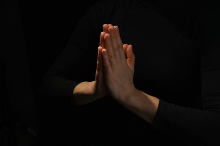 Religion. Christian woman praying on black background, closeupの写真素材