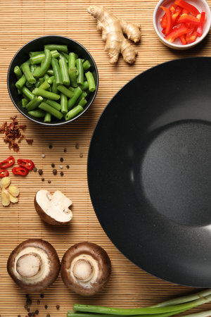Flat lay composition with black wok, spices and products on bamboo matの写真素材