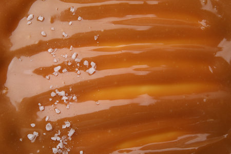 Delicious caramel sauce with sea salt as background, closeupの写真素材