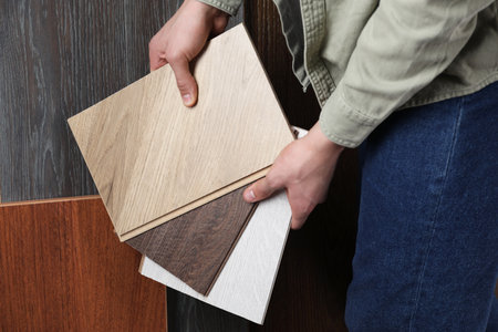 Man with different samples of wooden flooring indoors, closeupの写真素材