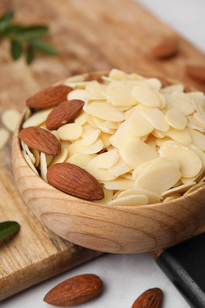 Fresh almond flakes and nuts in bowl on white table, closeupの写真素材