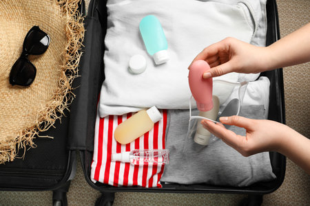 Woman putting small bottle with personal care product into plastic bag, closeup. Cosmetic travel kitの写真素材