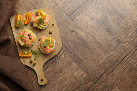 Tasty canapes with salmon served on wooden table, top view. Space for textの写真素材