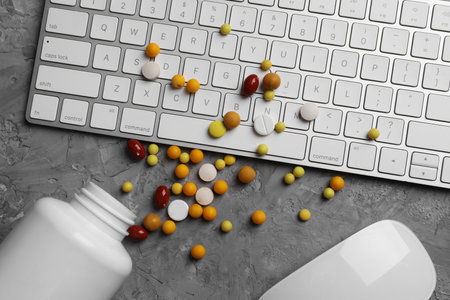 Medical supplement. Keyboard, mouse and pills on gray textured table, flat lay