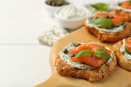 Tasty canapes with salmon, capers, cucumber and sauce on table, closeup. Space for text