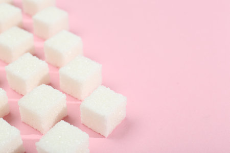 White sugar cubes on pink background, closeup. Space for textの写真素材