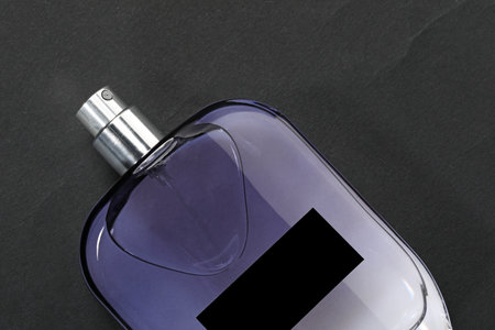 Luxury men`s perfume in bottle on black background, top view