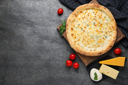 Delicious cheese pizza and ingredients on dark gray table, flat lay. Space for text