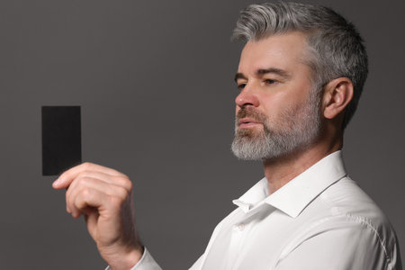 Handsome man holding blank business card on grey backgroundの写真素材