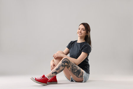 Smiling tattooed woman posing on grey backgroundの写真素材