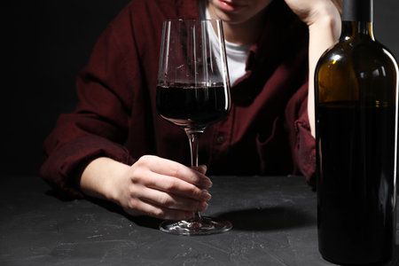 Alcohol addiction. Woman with red wine at dark textured table, selective focusの写真素材