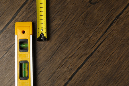 Building level and tape measure on wooden table, top view. Space for textの写真素材