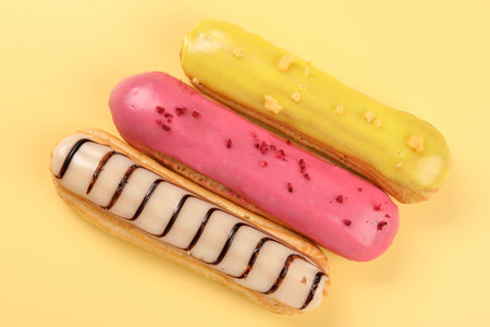 Delicious eclairs covered with glaze on yellow background, top viewの写真素材