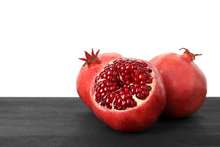 Fresh pomegranates on black wooden table against white background, space for textの写真素材