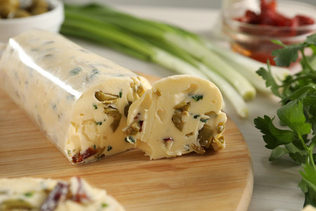 Tasty butter with olives, green onion and parsley on table, closeup
