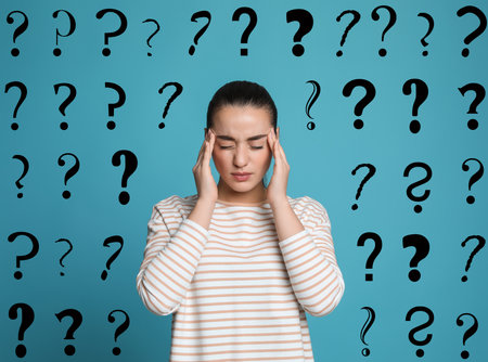 Amnesia. Confused young woman and question marks on light blue backgroundの写真素材