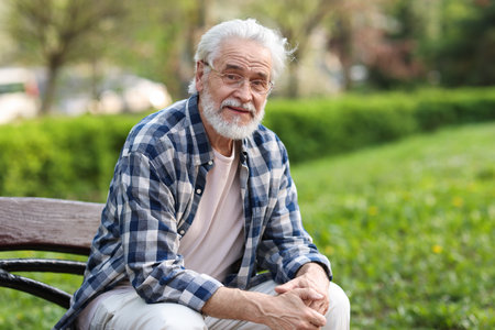 Portrait of happy grandpa with glasses on bench in parkの写真素材