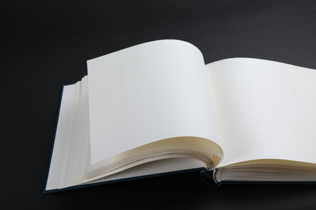 One open photo album on black background, closeup. Space for textの写真素材