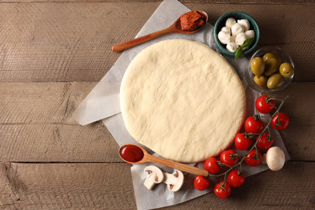 Pizza dough and products on wooden table, flat lay. Space for textの写真素材