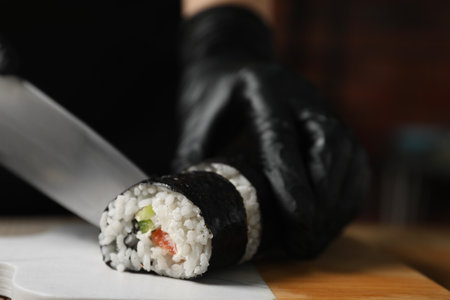 Chef in gloves cutting sushi roll at table, closeupの写真素材