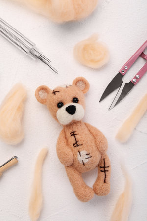 Felted bear, wool and tools on white table, flat layの写真素材