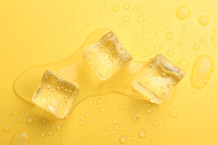 Crystal clear ice cubes on yellow background, flat layの写真素材