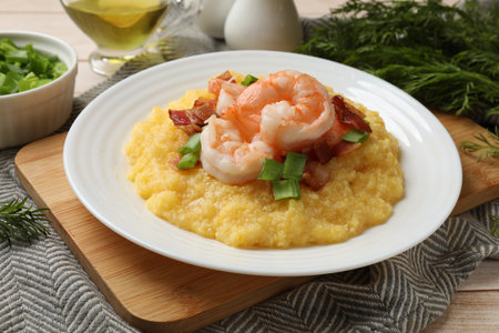 Plate with fresh tasty shrimps, bacon, grits and green onion on wooden tableの写真素材
