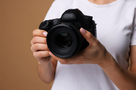 Photographer with camera on brown background, closeupの写真素材
