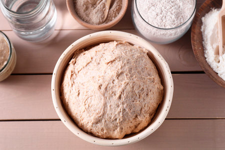 Fresh sourdough, flour and water on wooden table, flat lay