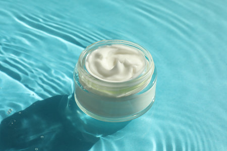 Jar with moisturizing cream in water on light blue backgroundの写真素材