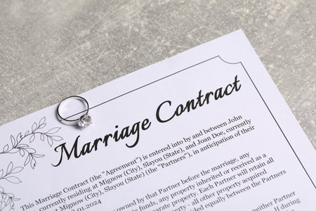 Marriage contract and ring with gemstone on gray table