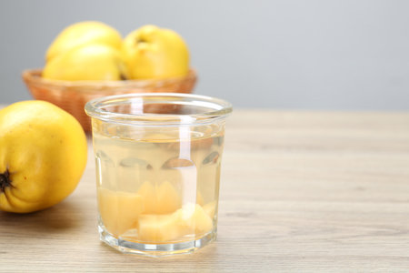 Delicious quince drink in glass and fresh fruits on wooden table, space for textの写真素材