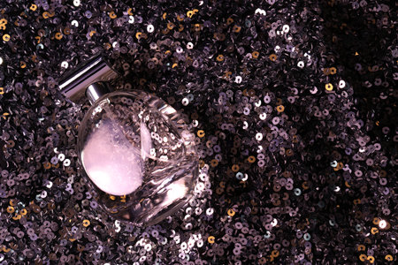 Luxury perfume in bottle on fabric with colorful sequins, top viewの写真素材
