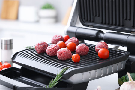 Meatballs, tomatoes and rosemary on electric grill indoors, closeupの写真素材