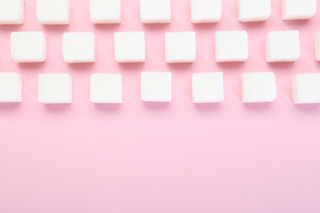 White sugar cubes on pink background, top view. Space for textの写真素材