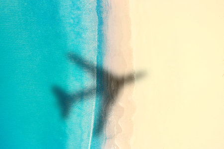 Shadow of airplane above beautiful sandy beach and sea, aerial view. Summer vacationの写真素材